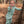 Child in a romper with a hood standing next to a tree in a forest