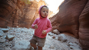 Child in a pink hoodie standing in a rocky canyon