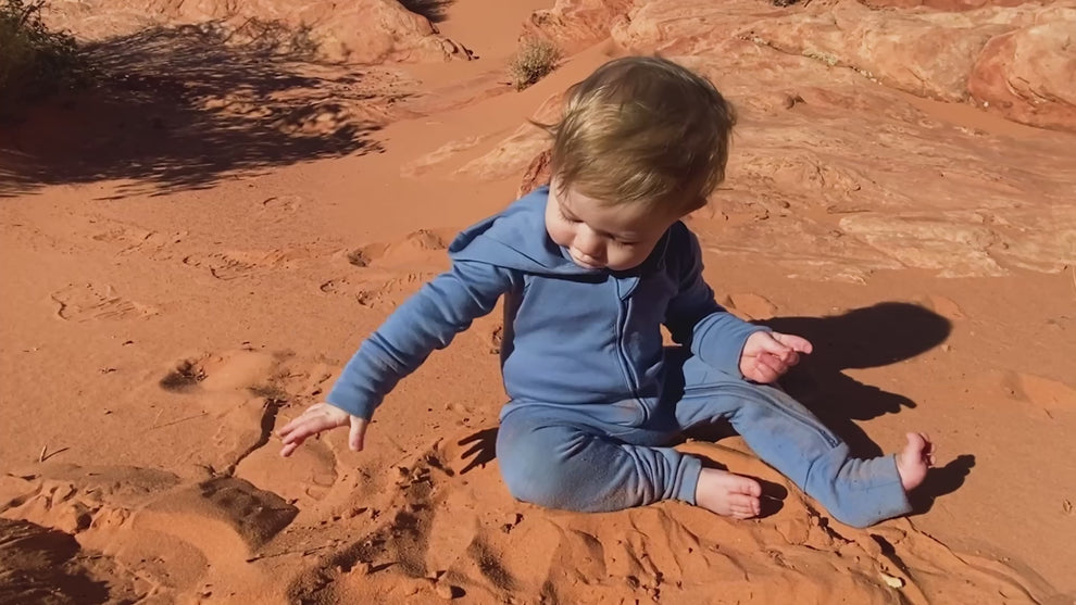 baby playing with sand in a desert